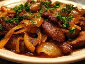 BœPlat de bœuf sauté aux oignons avec sa sauce brillante et caramélisée, garni de persil fraisuf sauté aux oignons dans une poêle en fonte