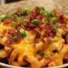 Des frites au four dorées et croustillantes, généreusement recouvertes de cheddar fondu et de morceaux de bacon grillé, parsemées d'oignons verts ciselés.