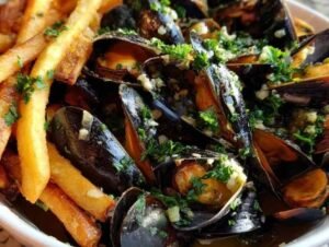 Un grand plat de moules marinières fumantes à côté d'un cornet de frites dorées, prêtes à être dégustées.
