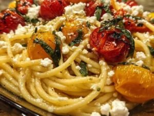 Assiette de pâtes crémeuses à la feta et aux tomates rôties, garnie de basilic frais.