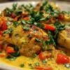 Un plat de service creux rempli de poulet coco antillais crémeux, garni de coriandre fraîche, avec du riz blanc à côté.