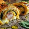 Roulé feuilleté au poulet, fromage et épinards, cuit et coupé en tranches, révélant la garniture fondante.