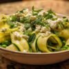 Salade de courgettes crues à la feta et petits pois servie dans une assiette blanche, vue de dessus.