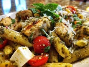 Gros plan sur les ingrédients de la salade de pâtes : poulet doré, tomates cerises, et mozzarella.