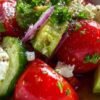 Ingrédients frais pour la recette de salade détox : concombre, tomates, avocat, oignon rouge, feta.