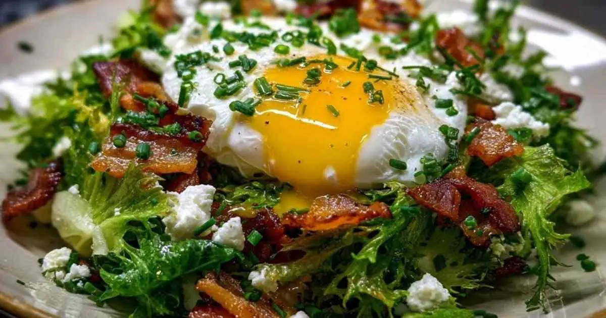 Gros plan sur le jaune d'œuf coulant d'un œuf poché sur une salade lyonnaise.