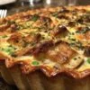 Tourte au poulet et aux champignons entière, avec une croûte dorée et feuilletée, servie dans son plat de cuisson.