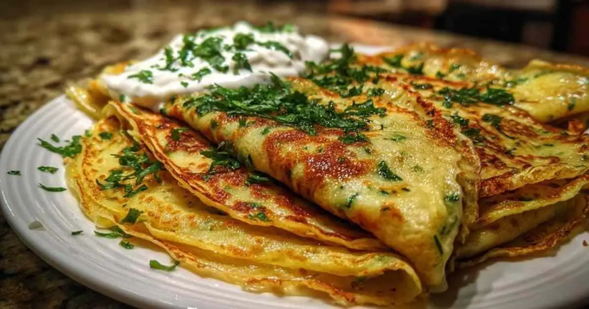 Assiette de crêpes de courgettes servies avec salade verte et sauce yaourt