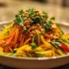 Salade de mangue thaï colorée dans un bol avec cacahuètes et coriandre