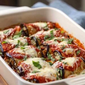 Aubergines roulées saines dorées dans un plat de cuisson avec sauce marinara