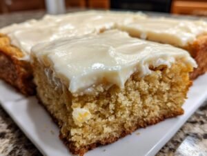 Gros plan sur des barres à la banane moelleuses recouvertes d'un glaçage blanc crémeux.