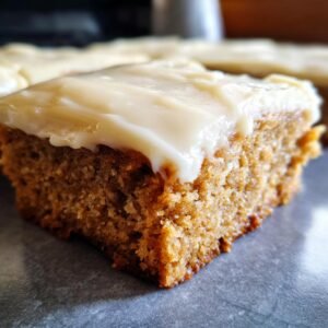 Gros plan d'une barre à la banane moelleuse avec un généreux glaçage blanc crémeux.
