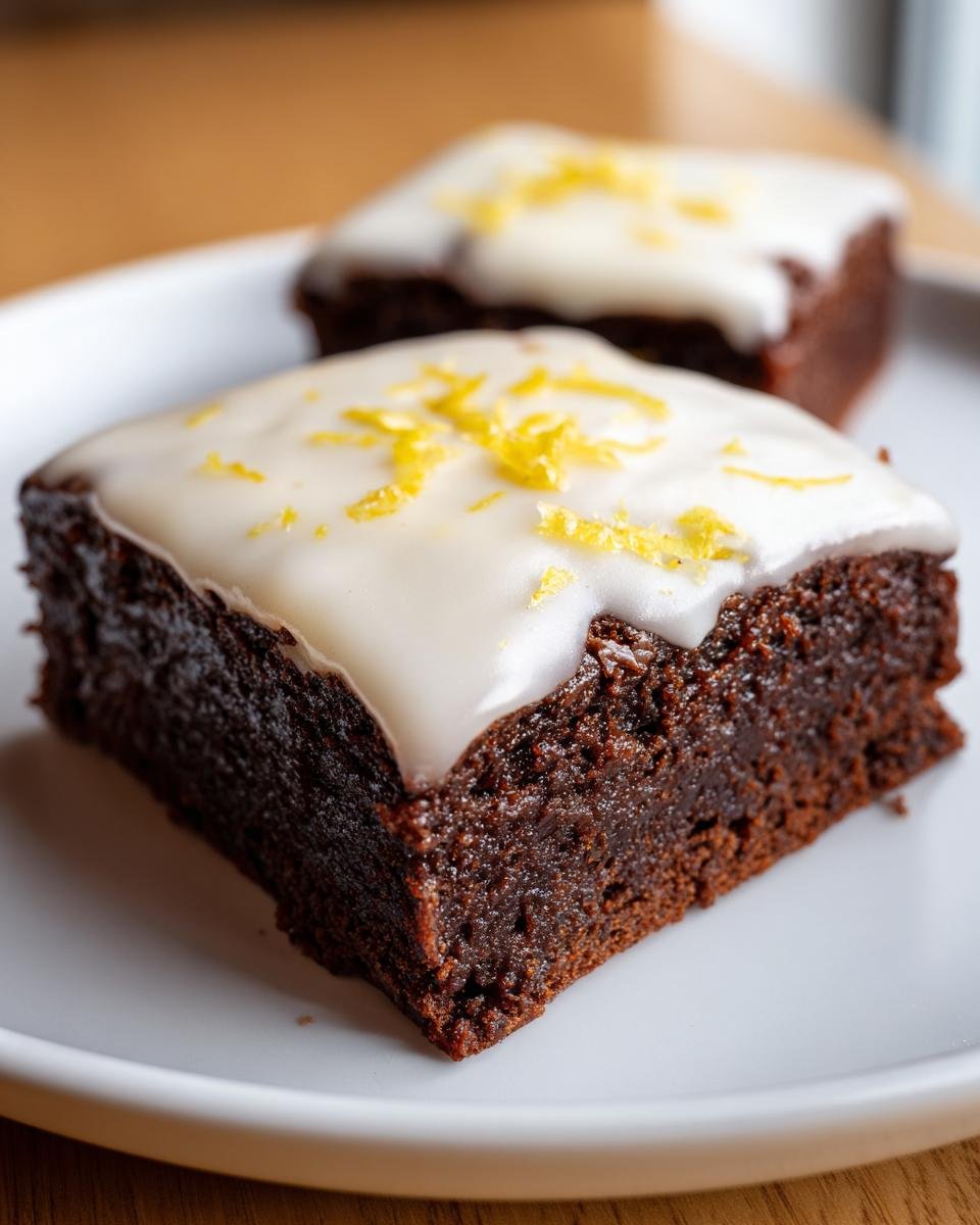 Brownies au Citron: 40 min, délice garanti 1 Gros plan sur deux brownies au citron glacés, garnis de zeste de citron frais.