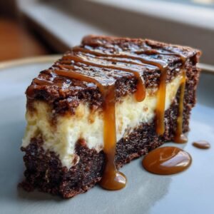 Gros plan sur une part de cheesecake brownie au caramel, avec un coulis de caramel dégoulinant.