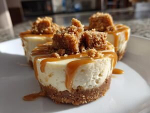 Gros plan sur des mini cheesecakes Biscoff sans cuisson garnis de miettes de Biscoff et de sauce caramel.