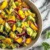 Salade colorée avec dés d'avocat et mangue dans un bol blanc