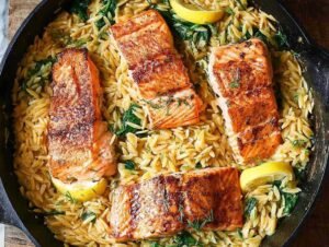 Saumon grillé sur lit d'orzo crémeux aux épinards dans une poêle