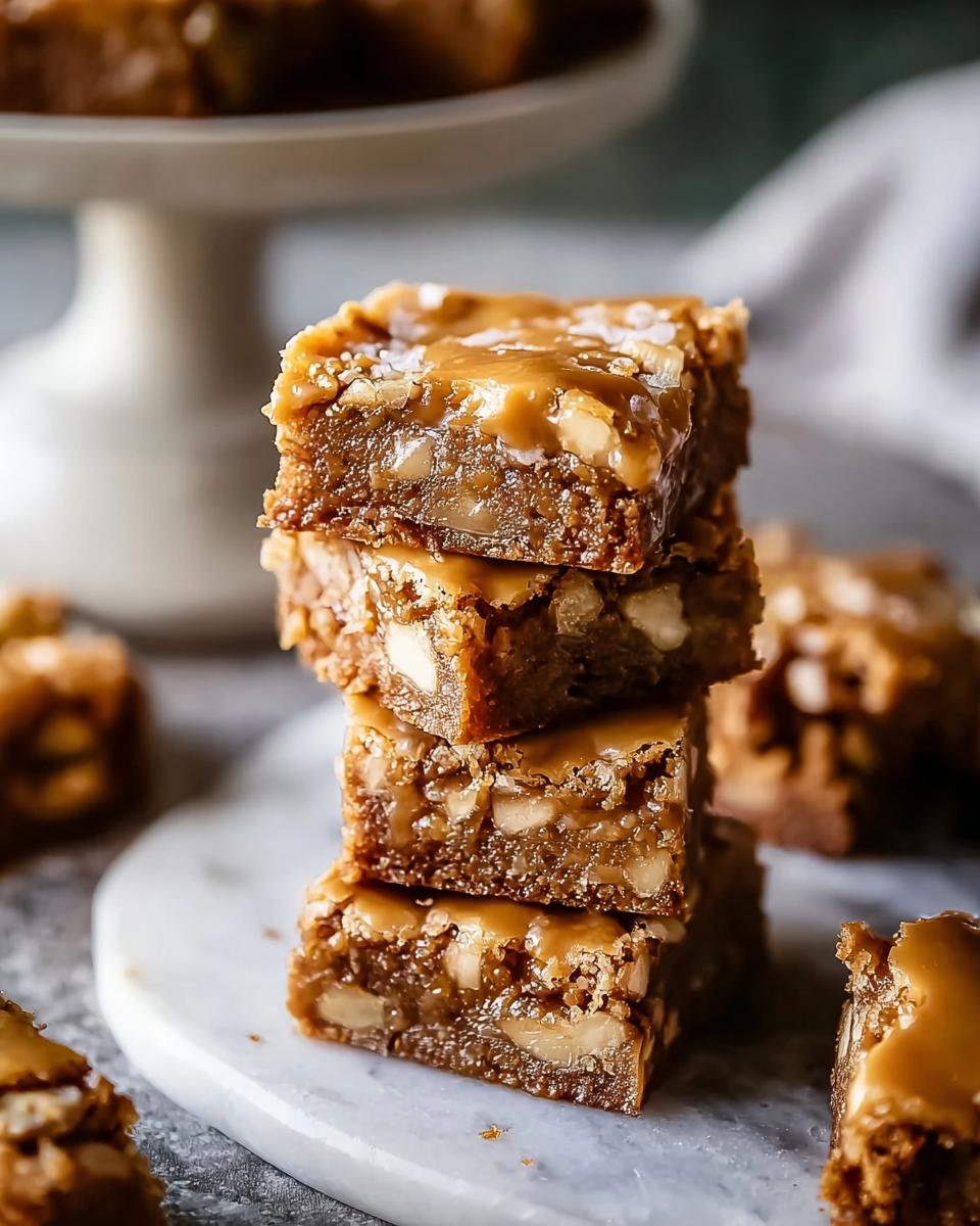 Gros plan d'une pile de blondies aux pommes et érable, nappés de caramel et parsemés de sel de mer.