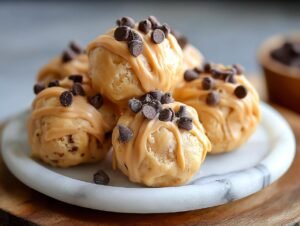 Bouchées glacées au yaourt grec : 1 recette miracle Gros plan de bouchées glacées au yaourt grec garnies de glaçage au beurre de cacahuète et de pépites de chocolat.