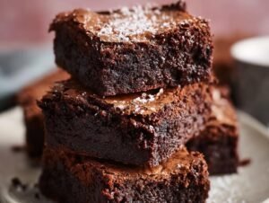 Gros plan sur une pile de brownies fondants au chocolat, saupoudrés de sucre glace.