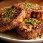 Gros plan sur des côtelettes de porc frites savoureuses, garnies de persil frais, servies dans une assiette.