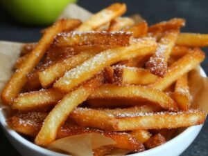 Gros plan sur des frites de pommes croustillantes saupoudrées de sucre, servies dans un bol.
