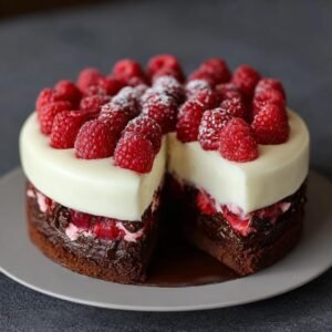 Gâteau Chocolat Blanc Framboises avec une part coupée, garni de framboises fraîches et de sucre glace.
