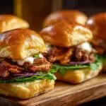 Gros plan sur des mini sandwichs au poulet et bœuf, garnis de laitue, oignon rouge et sauce.