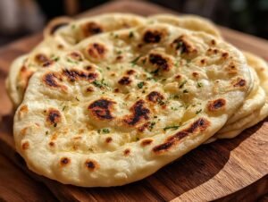 Gros plan de pains naan au levain jeté faits maison, dorés et parsemés de persil frais.