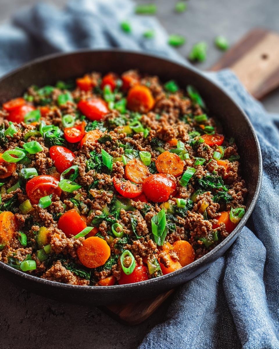 Plat de bœuf haché aux légumes colorés, carottes, tomates et oignons verts, prêt pour le meal prep.