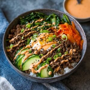 Bols Bulgogi Bœuf Haché: Saveur Intense 4 Gros plan d'un bol de Bulgogi bœuf haché garni d'un œuf au plat, de concombre, de carottes et de sauce.
