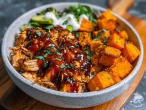 Bol Poulet BBQ : 3 secrets pour un délice Un bol de poulet BBQ effiloché, des cubes de patates douces rôtis et une salade verte avec une sauce blanche.